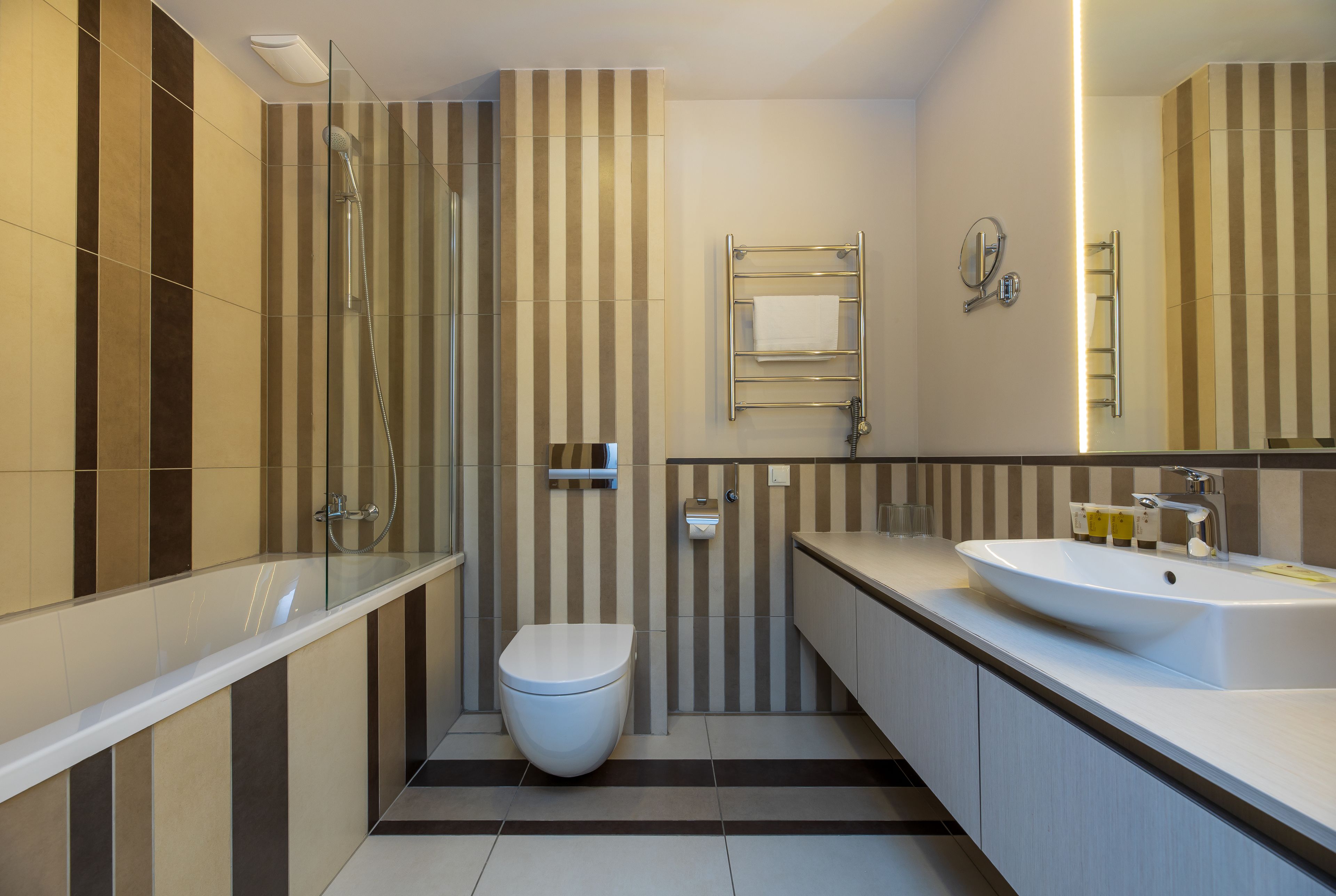 Un baño moderno con cabina de ducha de vidrio, inodoro blanco, tocador con lavamanos y espejo.