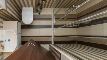 A modern bathroom with a wooden vanity, a glass shower enclosure, and striped wall tiles.