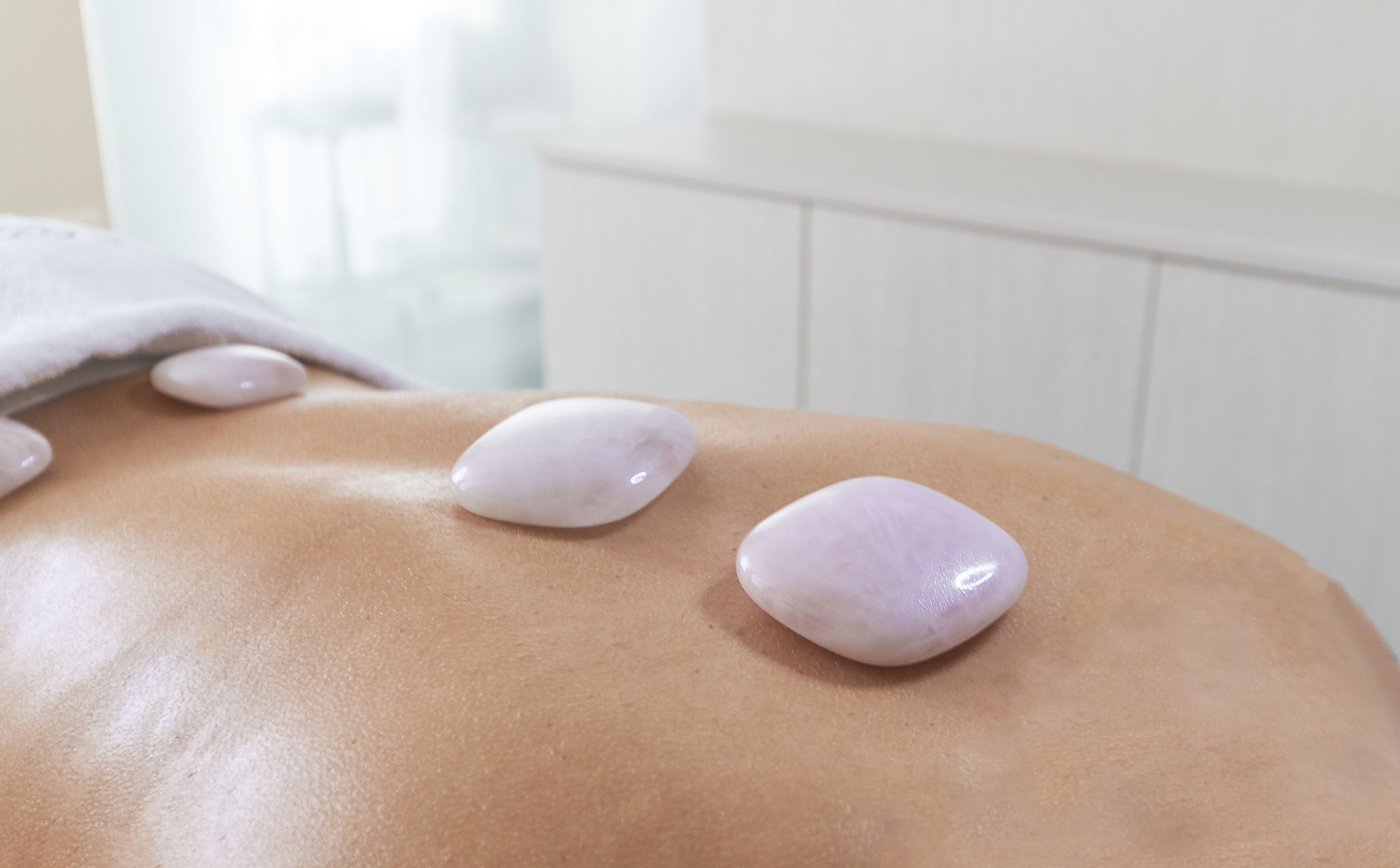A massage table with two smooth stones placed on a person's back.
