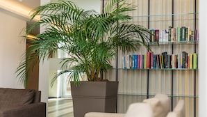 A modern living room with a large potted plant, a bookshelf, and a sofa. - Grand Baltic Dunes (Palanga)