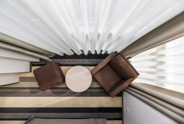A modern room with a striped floor, a round table, two brown sofas, and sheer curtains. - Grand Baltic Dunes (Palanga)