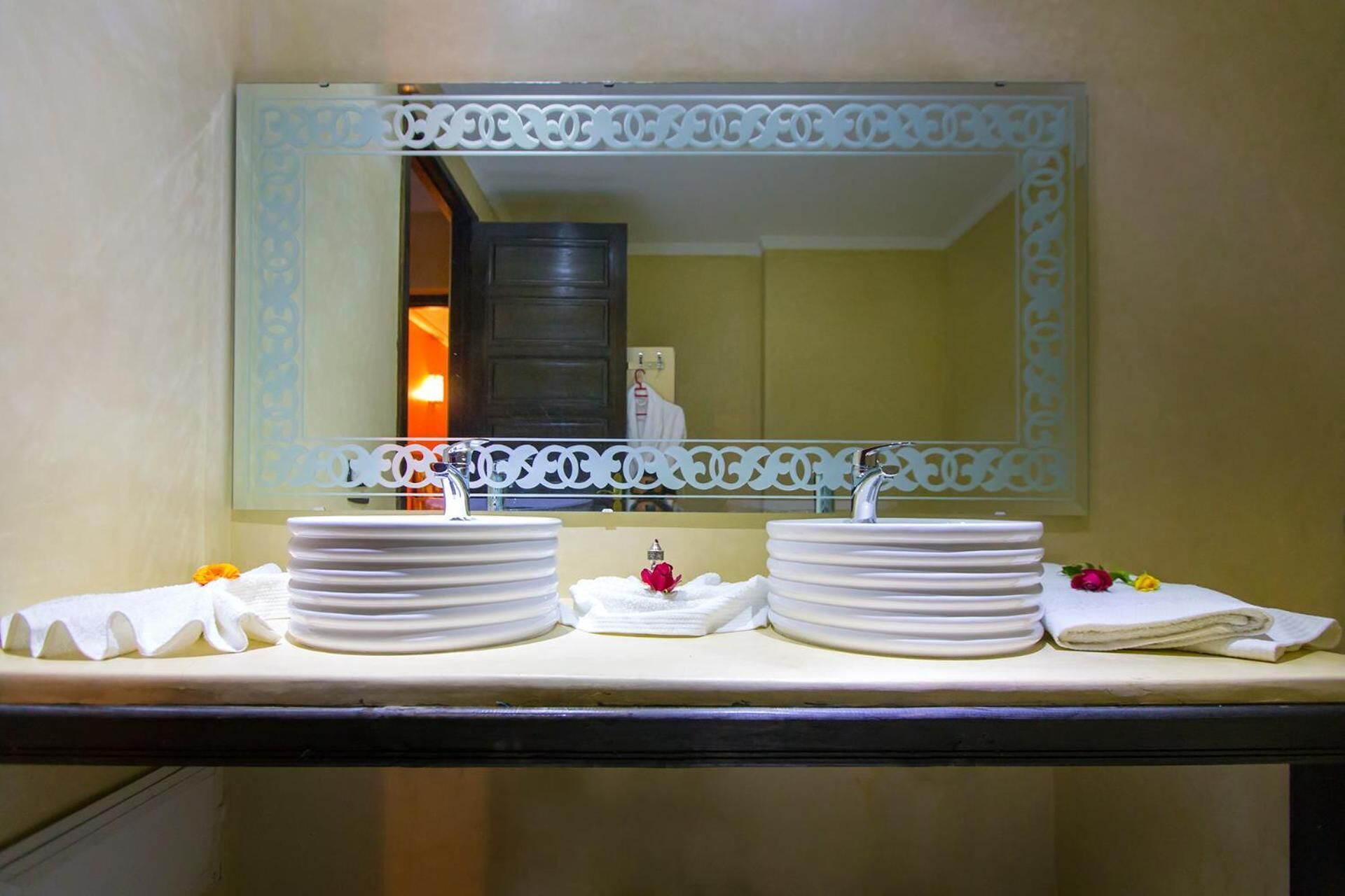 A bathroom with two sinks, a mirror with decorative frame, and towels on the counter.