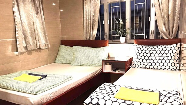 Ein Hotelzimmer mit zwei Betten, einem Nachttisch und einem Fenster mit Vorhängen.