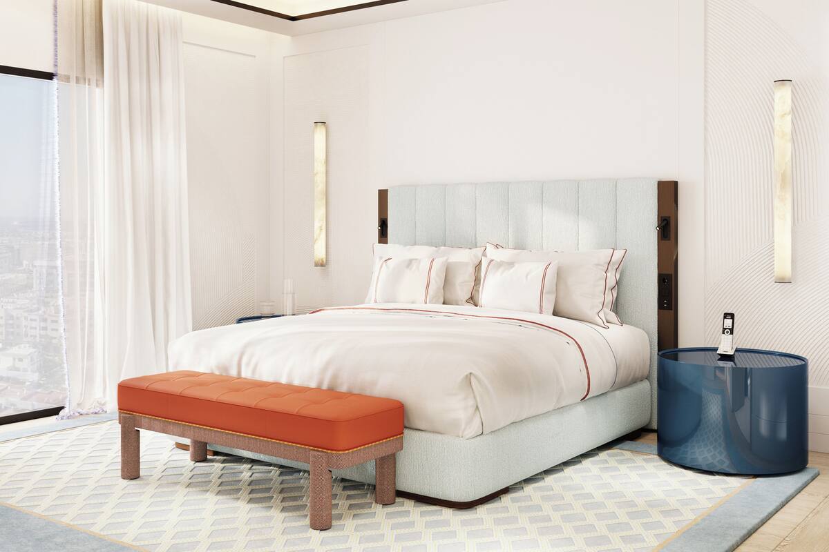 Una habitación de hotel moderna con una cama grande, un banco, una mesita de noche y vistas a la ciudad.