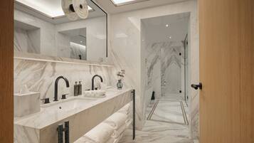 Un baño moderno con encimera de mármol, grifos negros y un espejo grande.