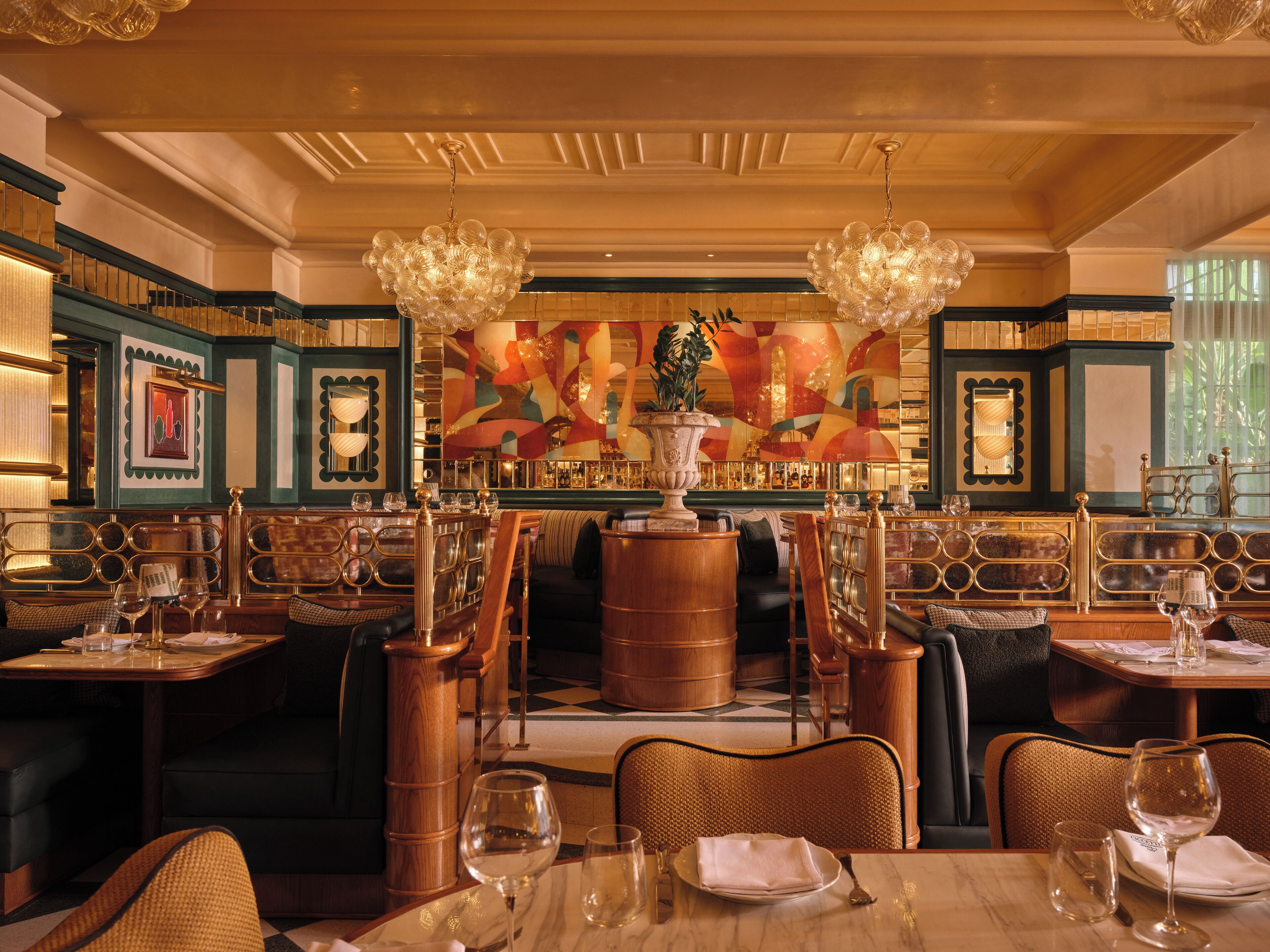 A luxurious dining area with ornate chandeliers, a central bar, and a vibrant abstract mural.