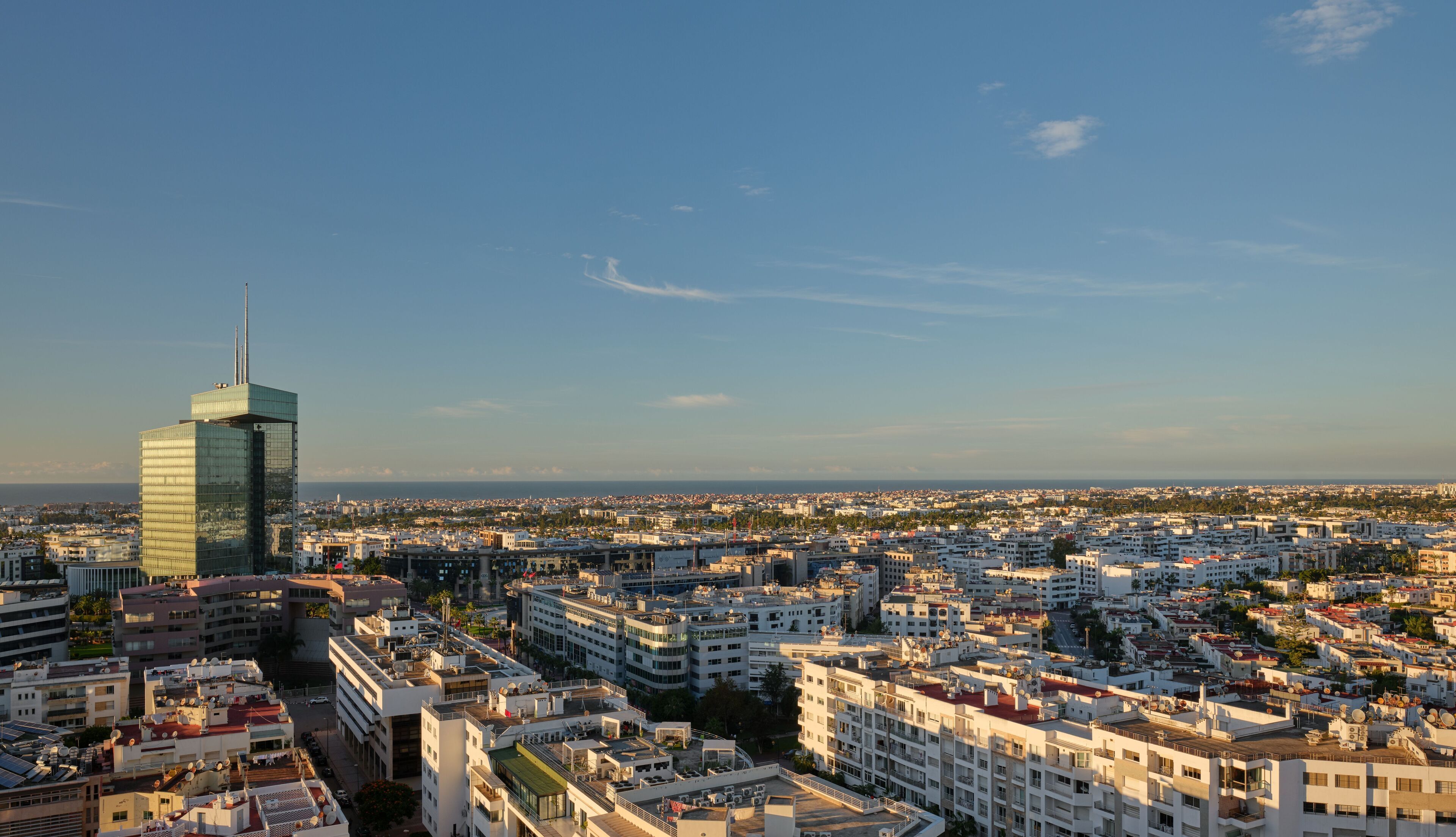 A cityscape with a prominent modern skyscraper, dense residential buildings, and a clear sky.