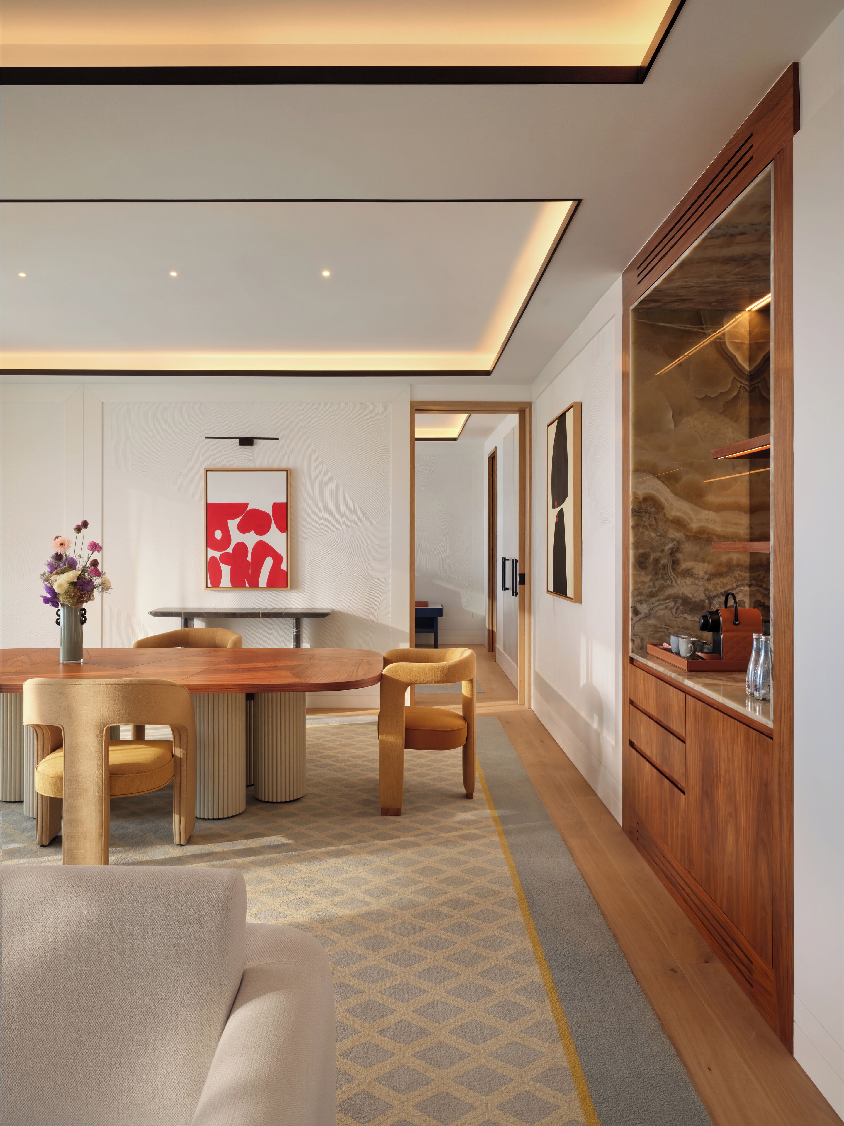 A modern dining area with a wooden table, chairs, and a vase of flowers.