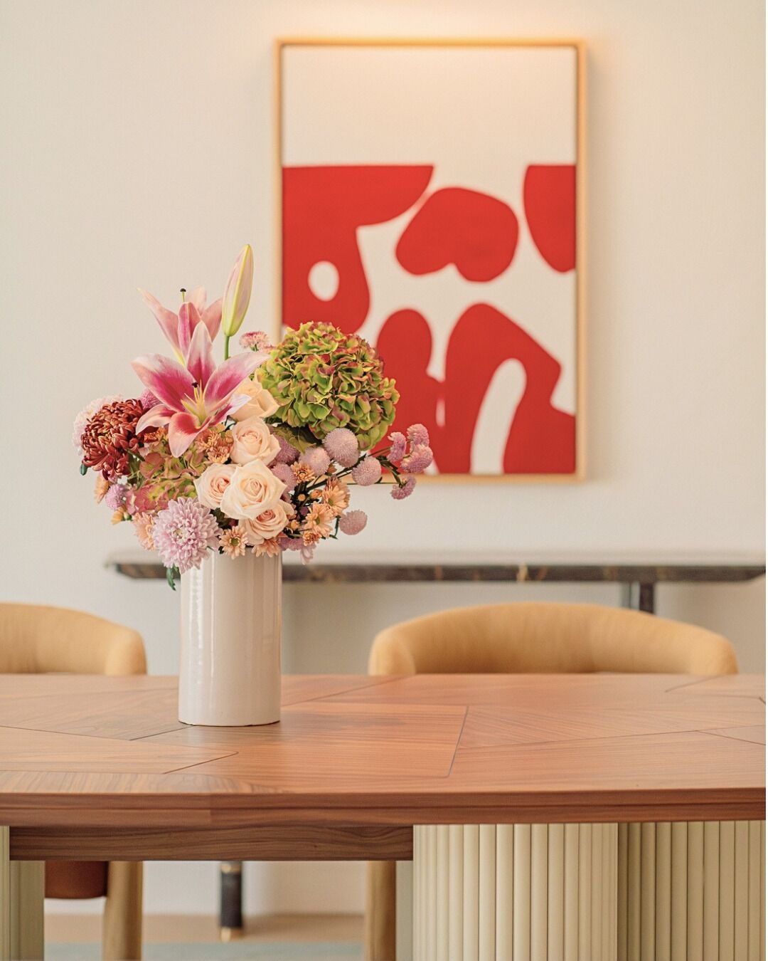 Ein Holztisch mit einer weißen Vase voller Blumen.
