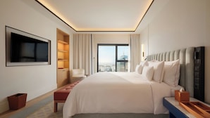 A modern hotel room with a large bed, a TV mounted on the wall, a seating area with a chair, and a view of the city through the window. - The View Rabat (Rabat)