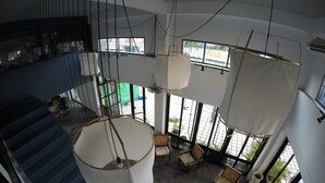 Un interior moderno con una escalera, lámparas colgantes y una zona de estar con vistas al exterior.
