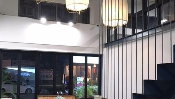 Un interior moderno con una escalera, una zona de estar y grandes ventanales.