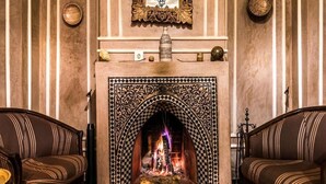 Una habitación con chimenea decorada con motivos, dos sofás y adornos en las paredes.