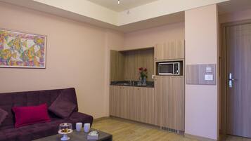 A compact living space with a sofa, a coffee table, a microwave, and a sink in a kitchenette.