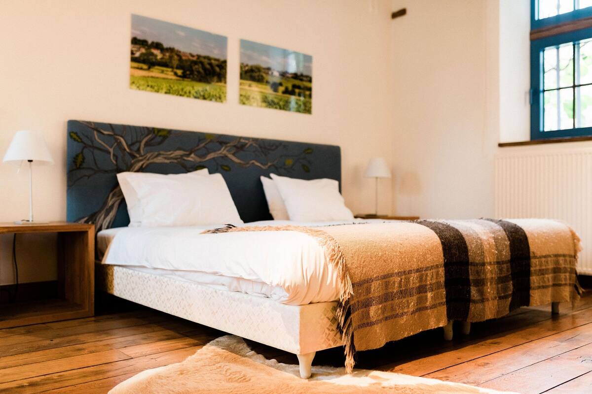 A double bed with a headboard, two bedside tables, and a window with a view of the outdoors.
