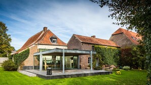 A modern house with a glass conservatory, brick walls, and a well-maintained lawn. - Indrani Lodge (Genappe)