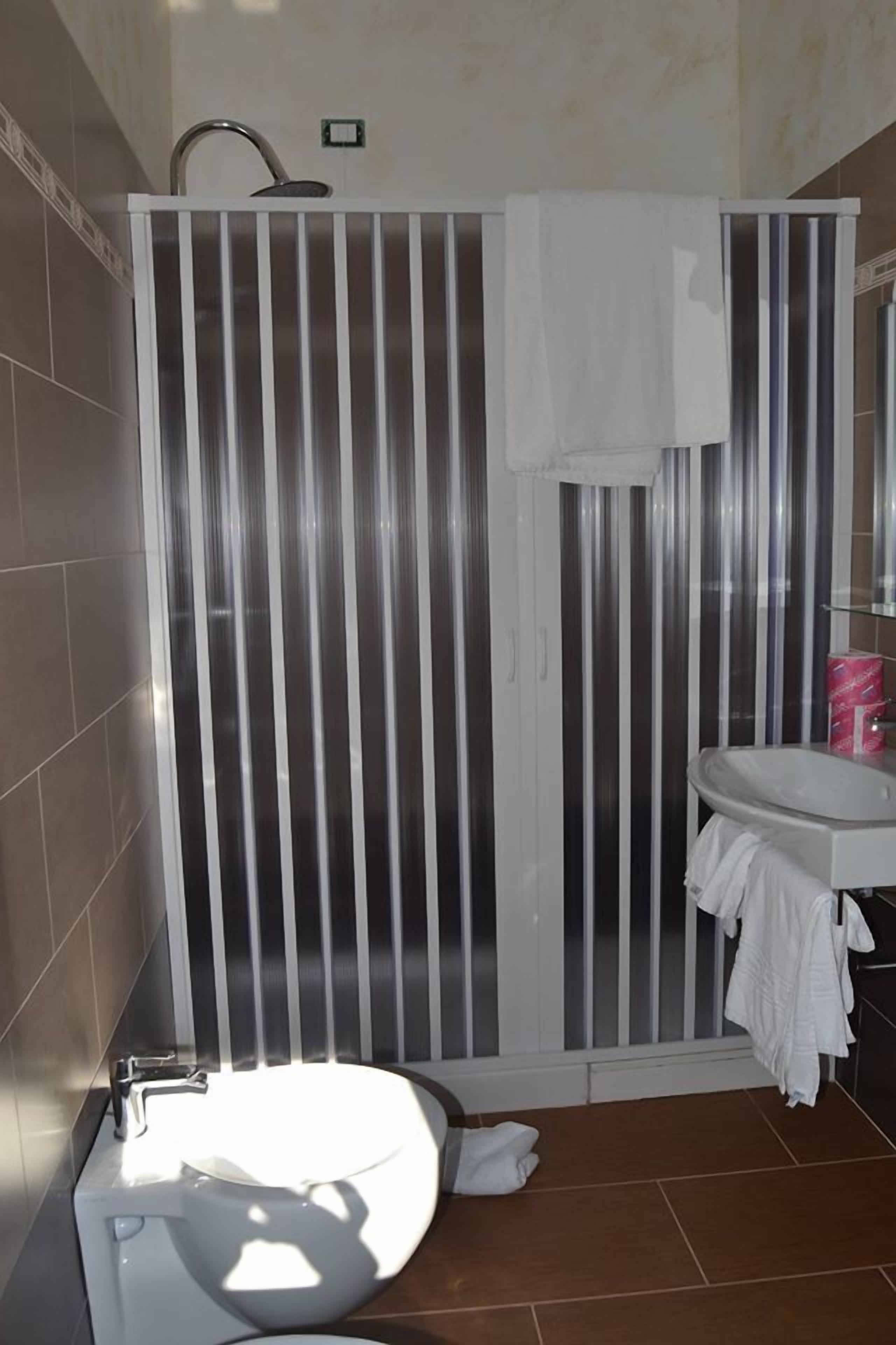A bathroom with a shower enclosure, a sink, and a mirror.