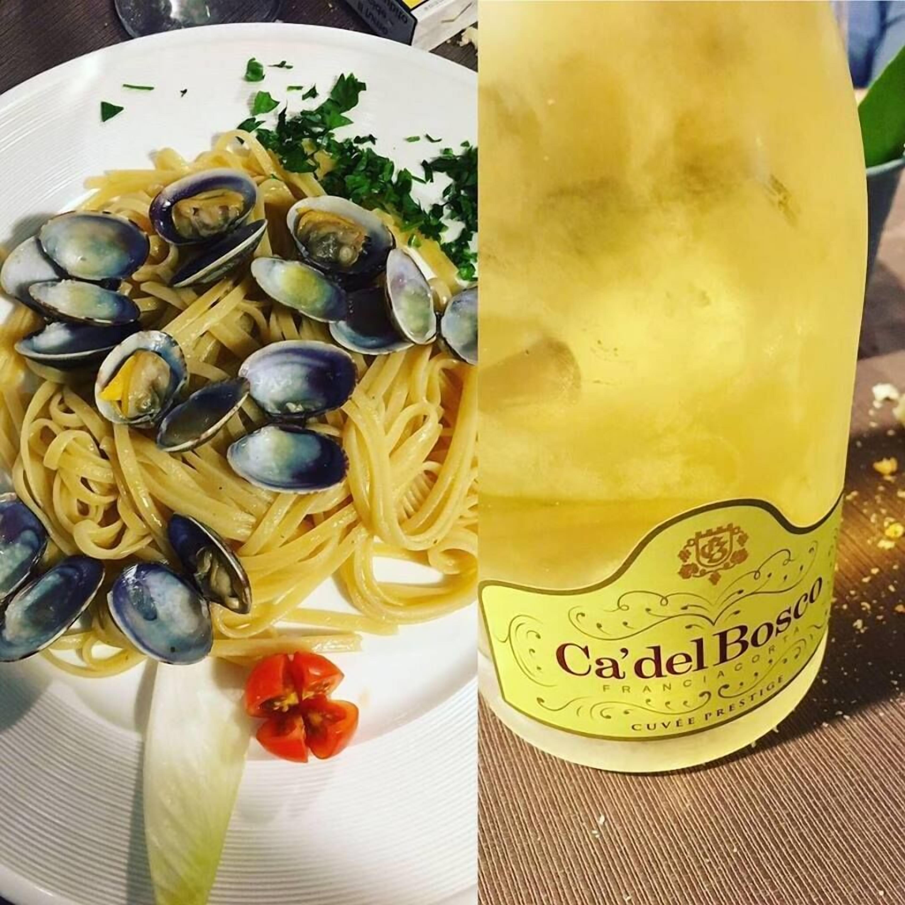 Un piatto di spaghetti con cozze e una bottiglia di vino Cà del Bosco.