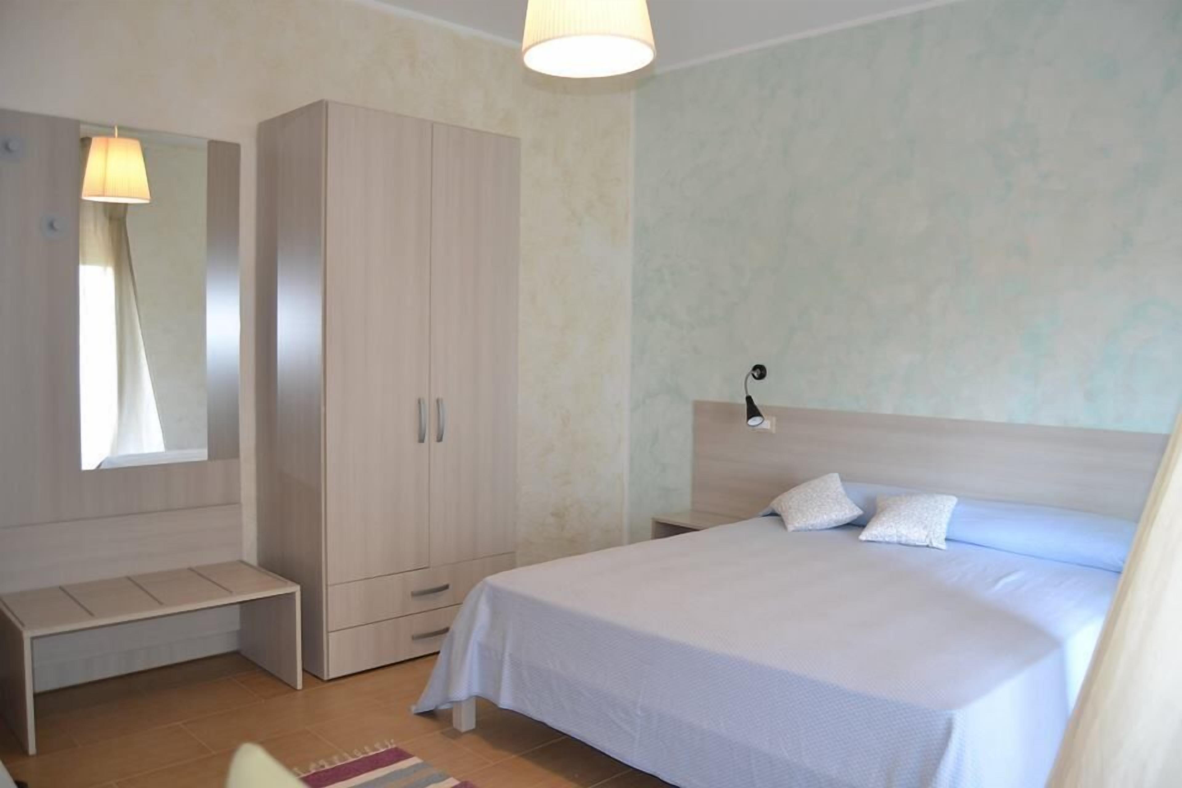 Ein Schlafzimmer mit einem Bett, einem Kleiderschrank, einer Bank und einem Nachttisch.