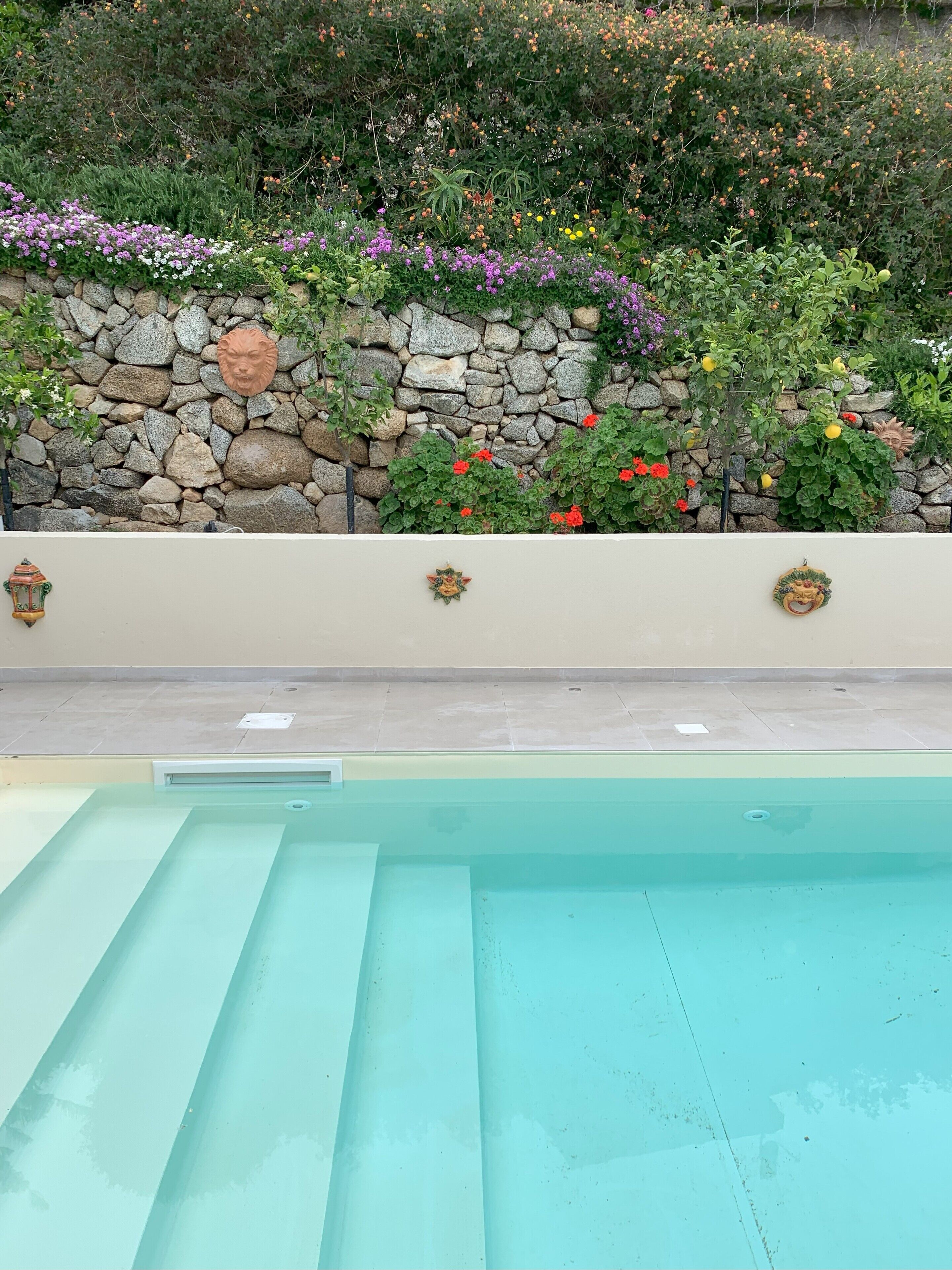 Une piscine avec un mur en pierre et des éléments décoratifs.