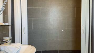 A bathroom with a shower enclosure, a sink, and a mirror.