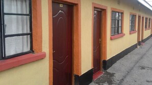 A row of doors with numbers 05 and 06, indicating room numbers, on a building with a yellow exterior and black trim. - Sleepway Cottages (Nakuru)