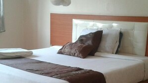 A neatly made bed with a brown throw blanket, white linens, and two pillows.