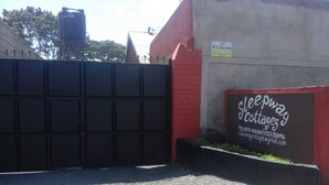 A gated entrance to a property with a sign for 'Sleepway Cottages' and contact information. - Sleepway Cottages (Nakuru)