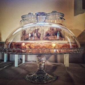 A glass-covered dessert display with three sections on a pedestal. - Agriturismo Borgo Tecla (Rosa)
