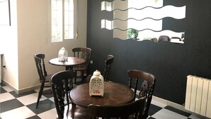Un espace repas avec un mur noir, un miroir à cadre blanc et un sol à carreaux.