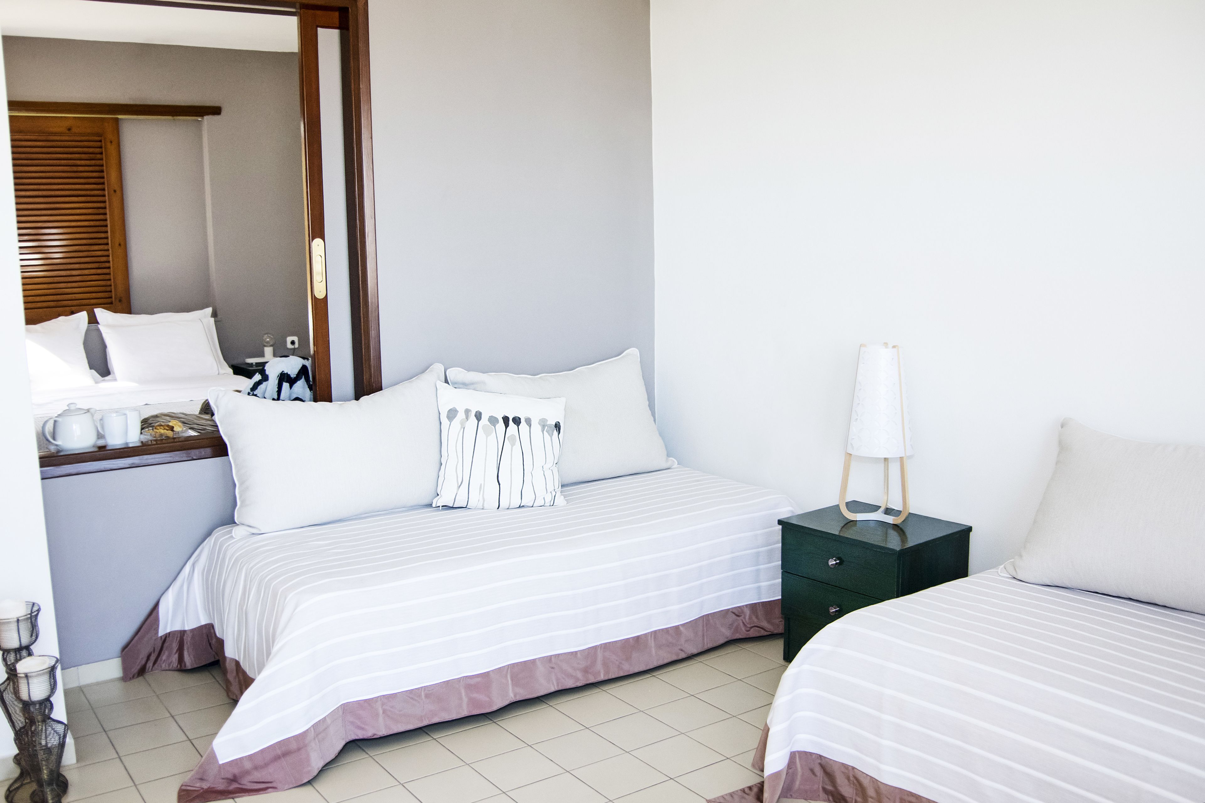 Une chambre d’hôtel avec deux lits, une table de chevet, une lampe et un miroir.