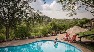 Alberca al aire libre, sombrillas en la alberca y camastros