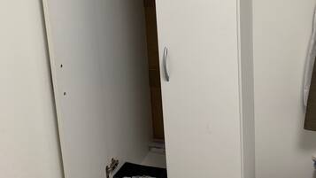 A white wardrobe with a handle, a black storage box, and a small drawer.