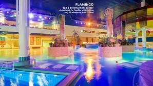 A spacious indoor swimming pool area with multiple levels, surrounded by potted plants and a brightly lit ceiling. - Wonderful Helsinki Apartment (Helsinki)