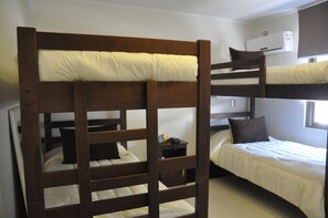A bunk bed room with a wooden headboard, a bedside table with a phone, and a window with an air conditioning unit. - Cosmopolita Hostel (Santiago)