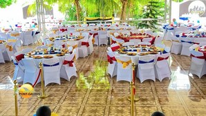 Un espacio para eventos interior con mesas redondas, manteles blancos y cintas rojas y blancas.