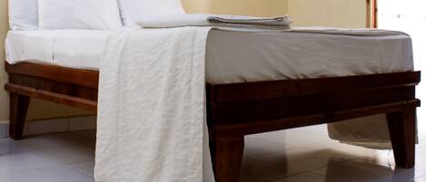 Un dormitorio con cama de madera, ropa de cama blanca y un cuadro enmarcado en la pared.