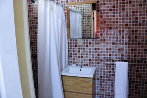 Un baño con lavamanos blanco, mueble de madera y pared de azulejos.