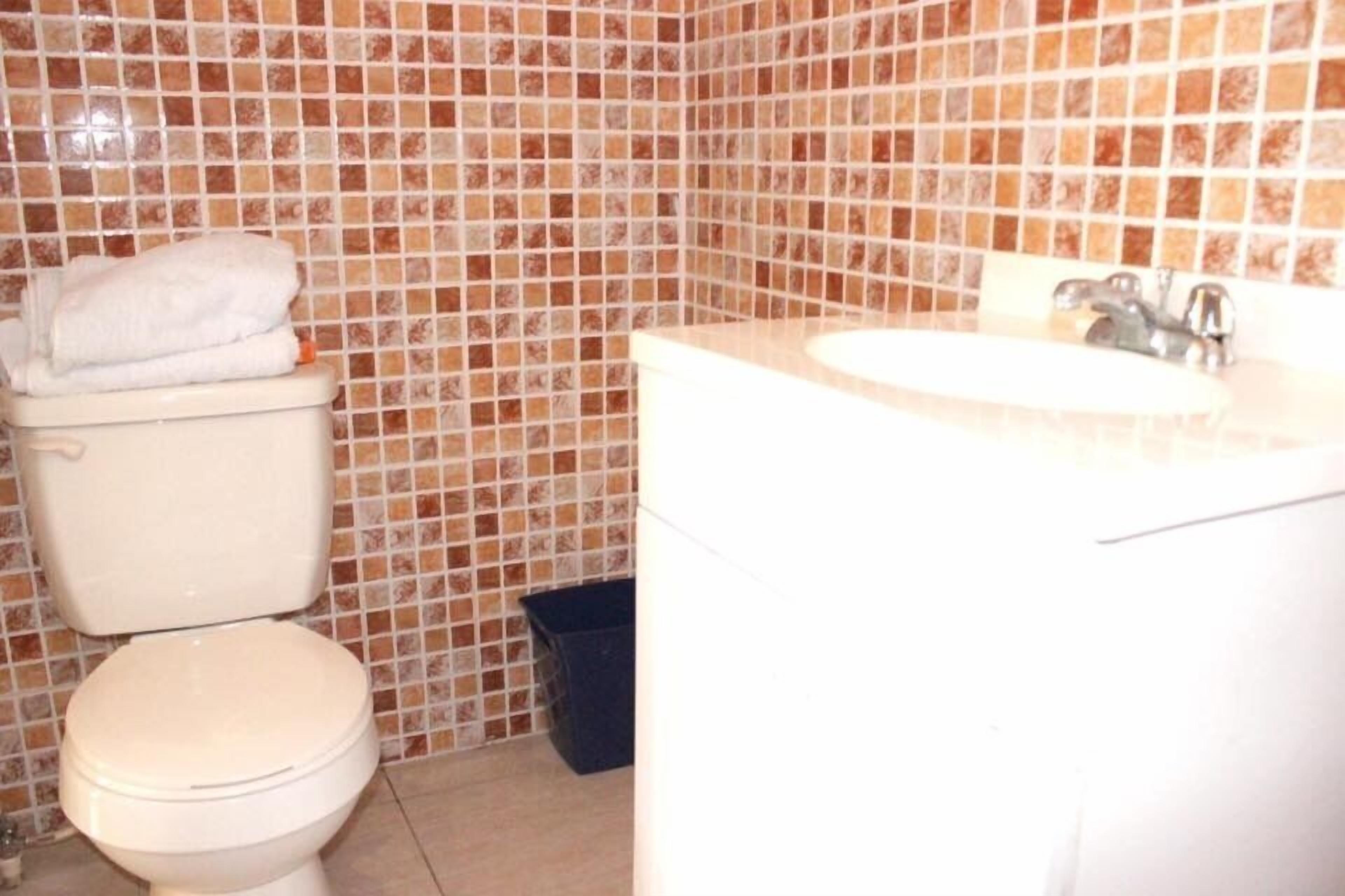 Une salle de bain avec des toilettes, un lavabo et des murs carrelés.