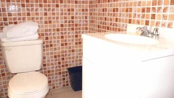Une salle de bain avec des toilettes, un lavabo et des murs carrelés.