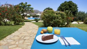 A table with a slice of cake, an apple, a kiwi, and a glass of orange juice. - Ulivo Blu Casa Vacanze (Castellammare del Golfo)