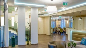 Un moderno vestíbulo de hotel con mostrador de recepción, zona de estar y una escalera.
