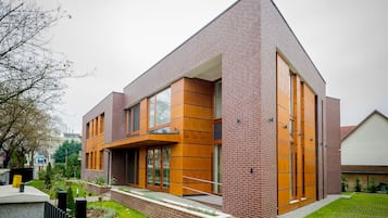 Situated in a landscaped area, this building features a combination of brick and wooden facade elements, large windows, and a flat roof.