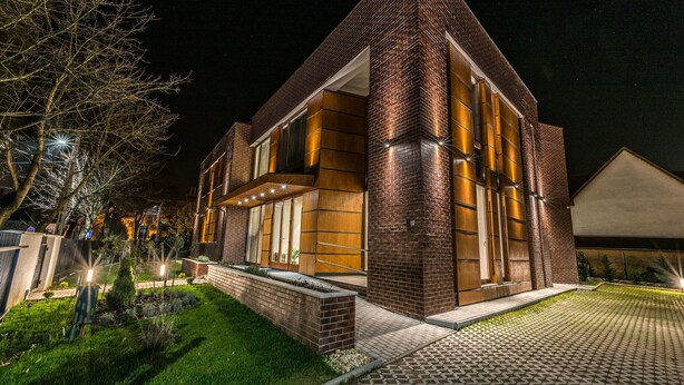 Una casa moderna con fachada de ladrillo, ventanas amplias y una entrada bien iluminada.
