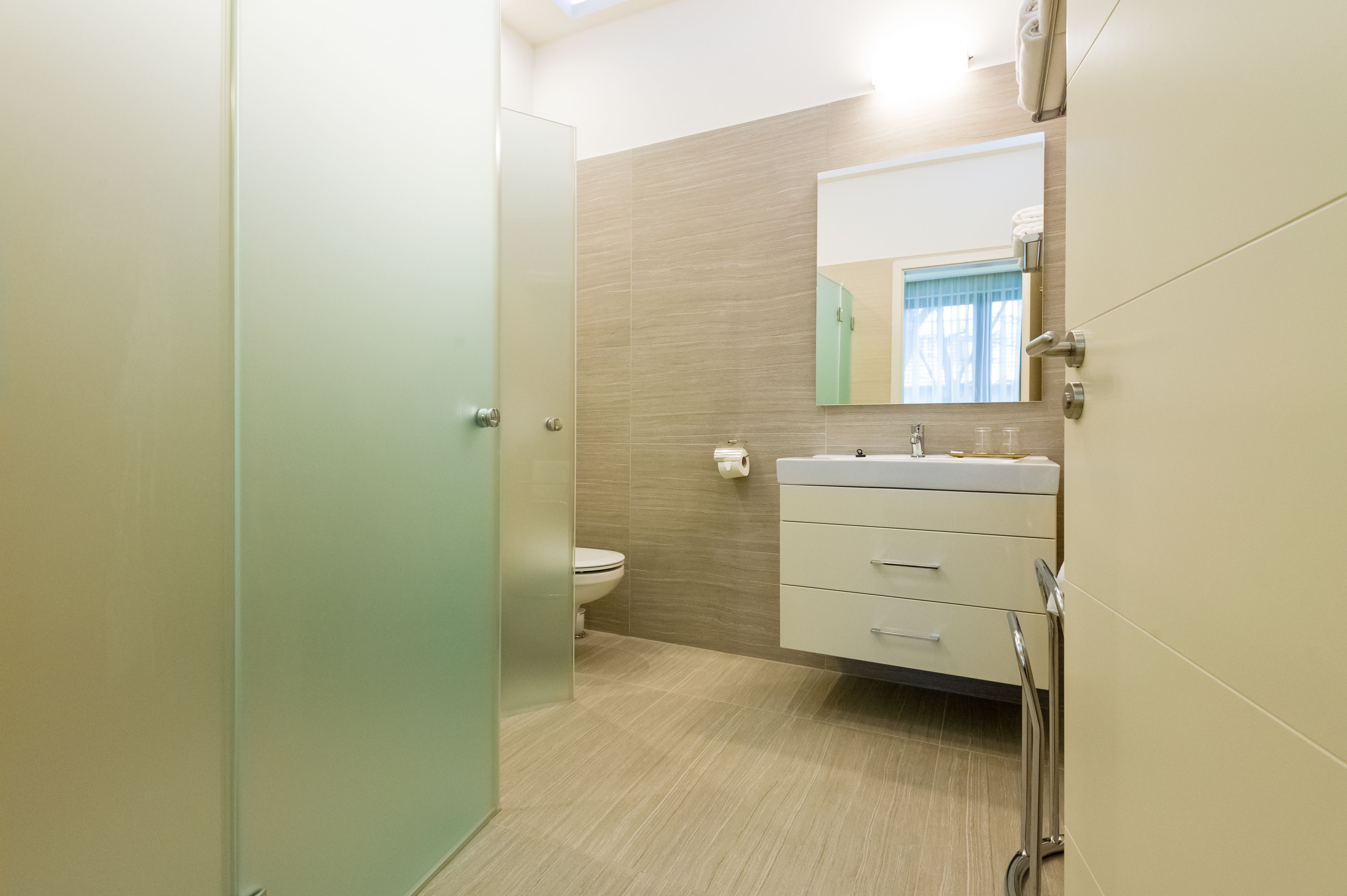 Un baño moderno con inodoro, lavamanos y espejo.