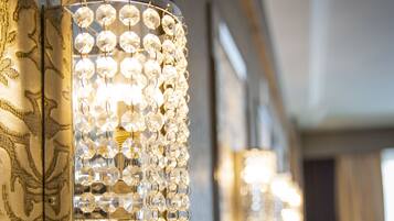 A wall-mounted light fixture with multiple clear crystal elements.