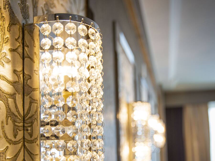 A wall-mounted light fixture with multiple clear crystal elements.