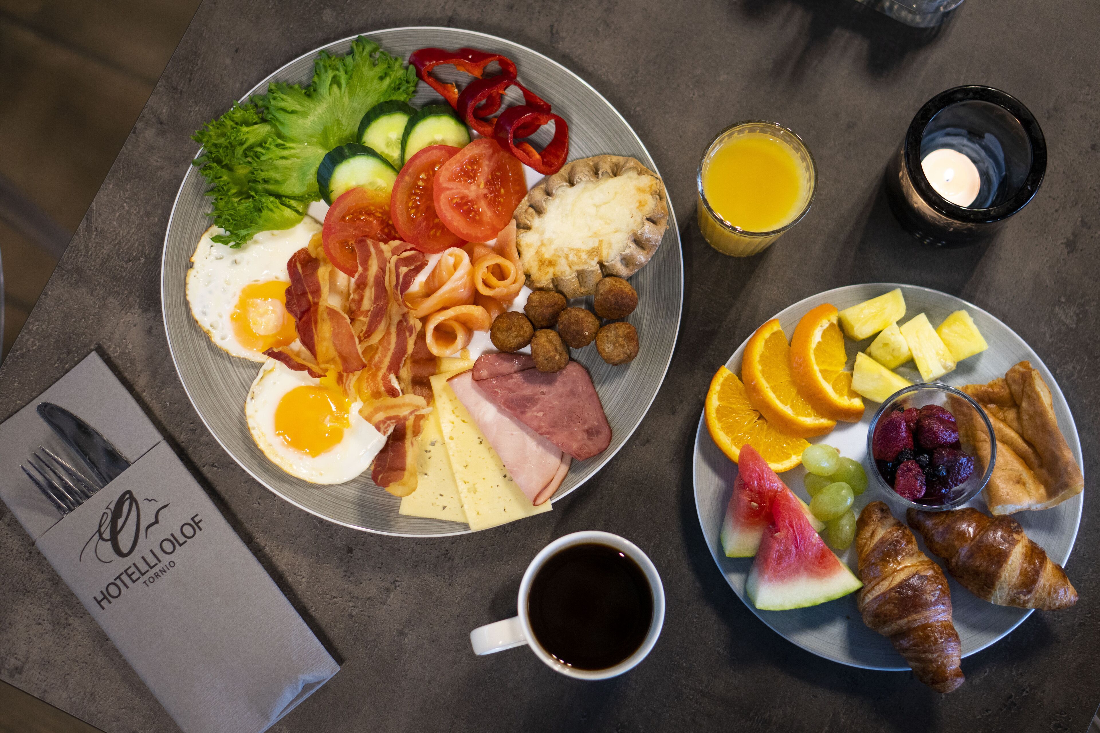 A breakfast plate with eggs, bacon, ham, cheese, and vegetables.