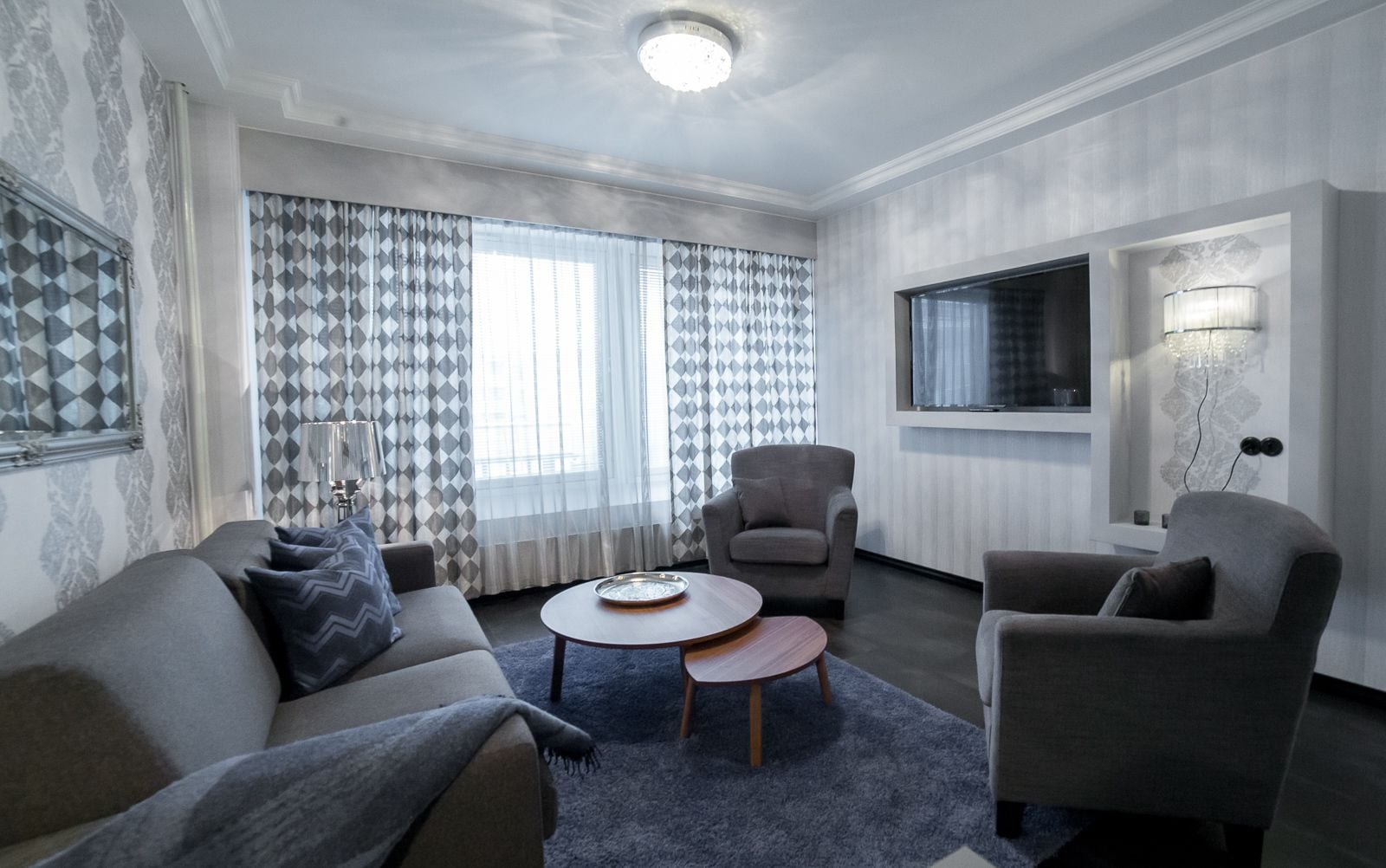 Una sala moderna con un sofá, sillones, una mesa de centro y un televisor.