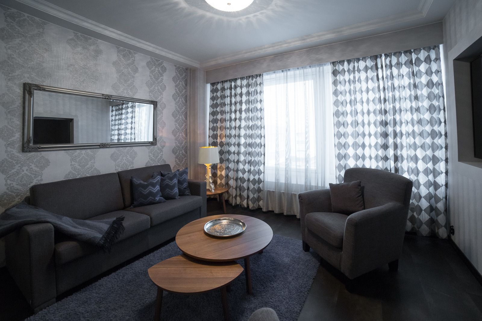 A living room with a sofa, armchair, and round wooden coffee table.